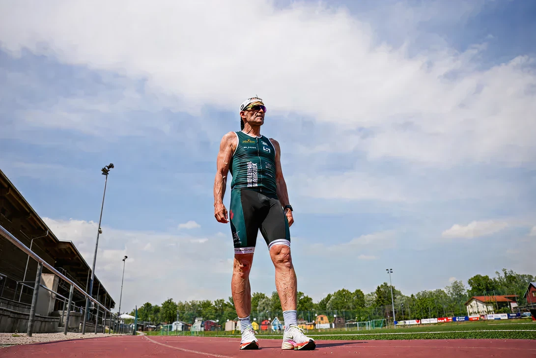 „Triathlet Paul Marouschek im grünen Wettkampfanzug steht auf einer Laufbahn und blickt in die Ferne“